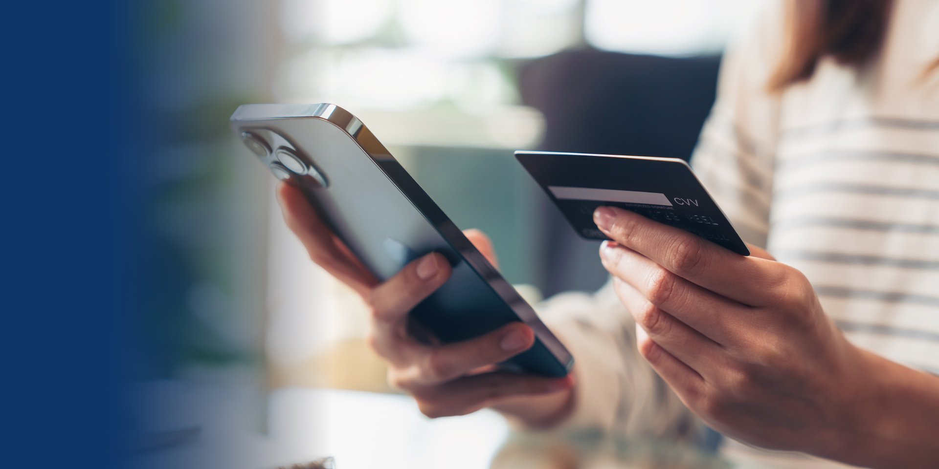 Close up of a woman's hands holding her phone and her debit card