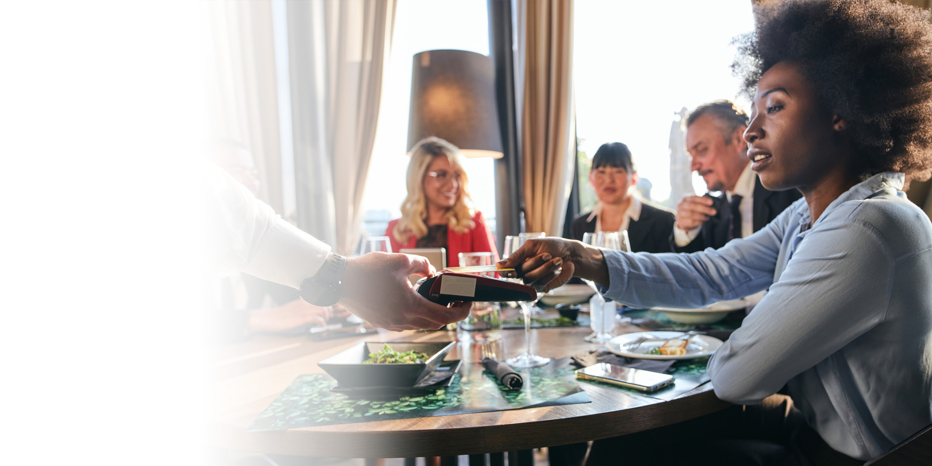 A business owner at a dinner meeting paying by credit card