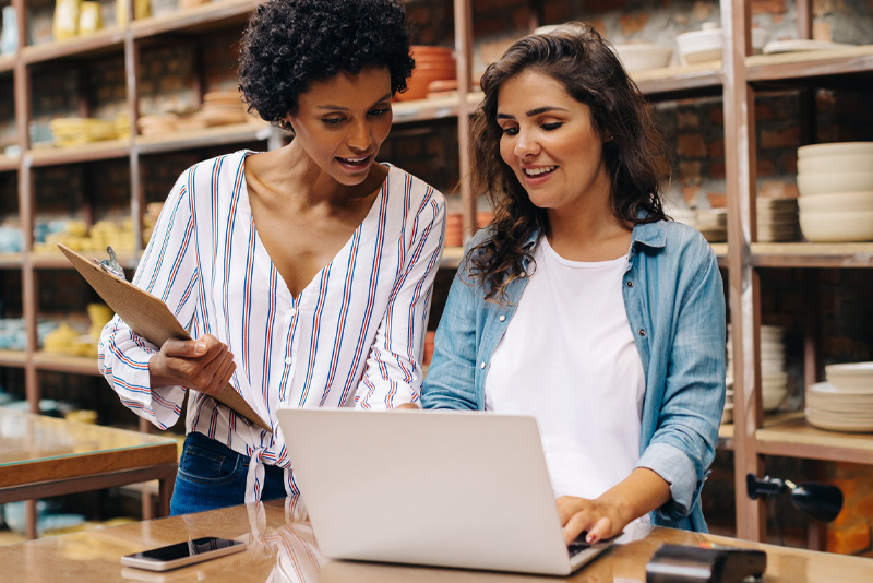 Two workers looking at loan options on a laptop