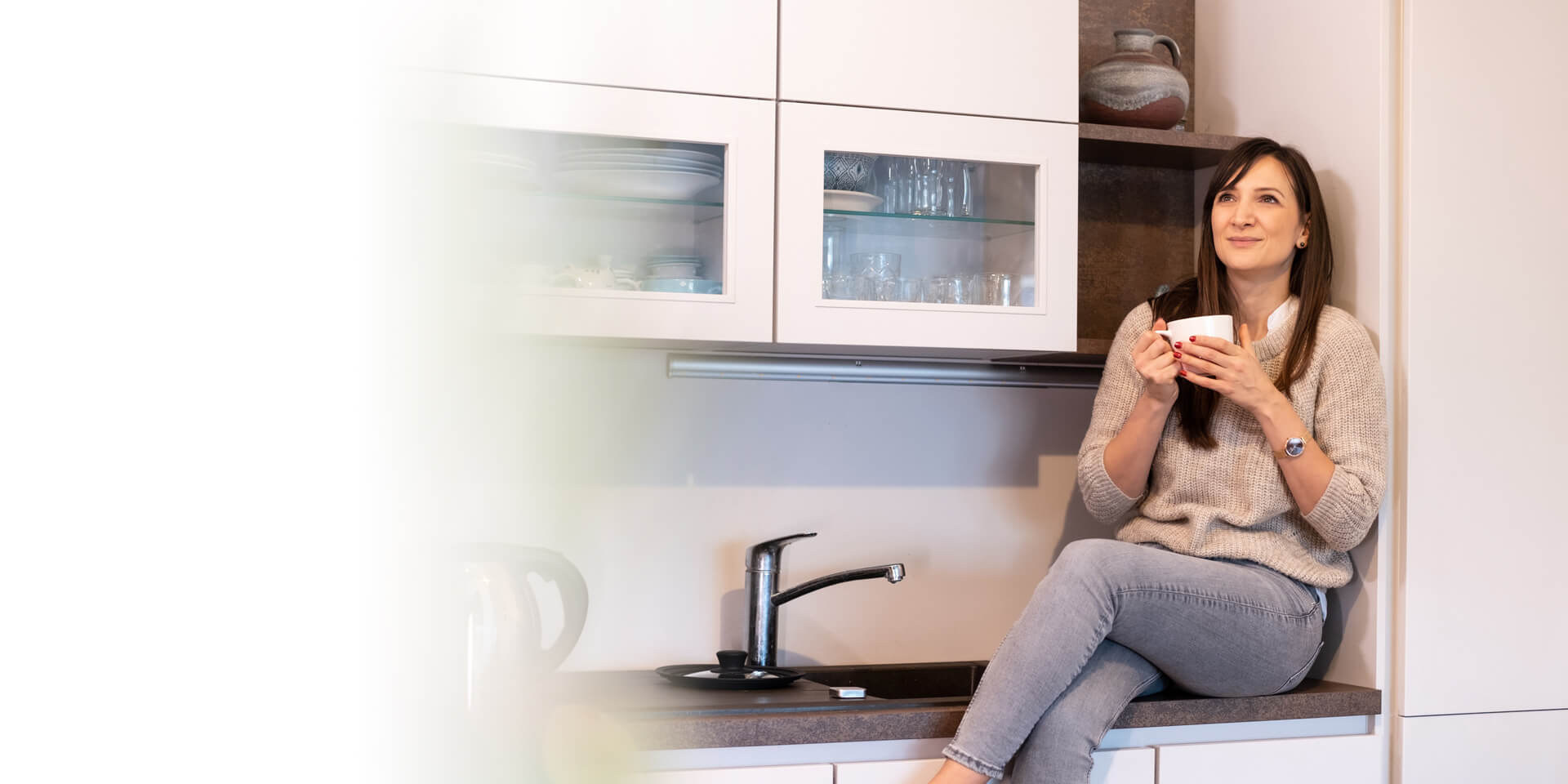 A woman in her kitchen drinking coffee